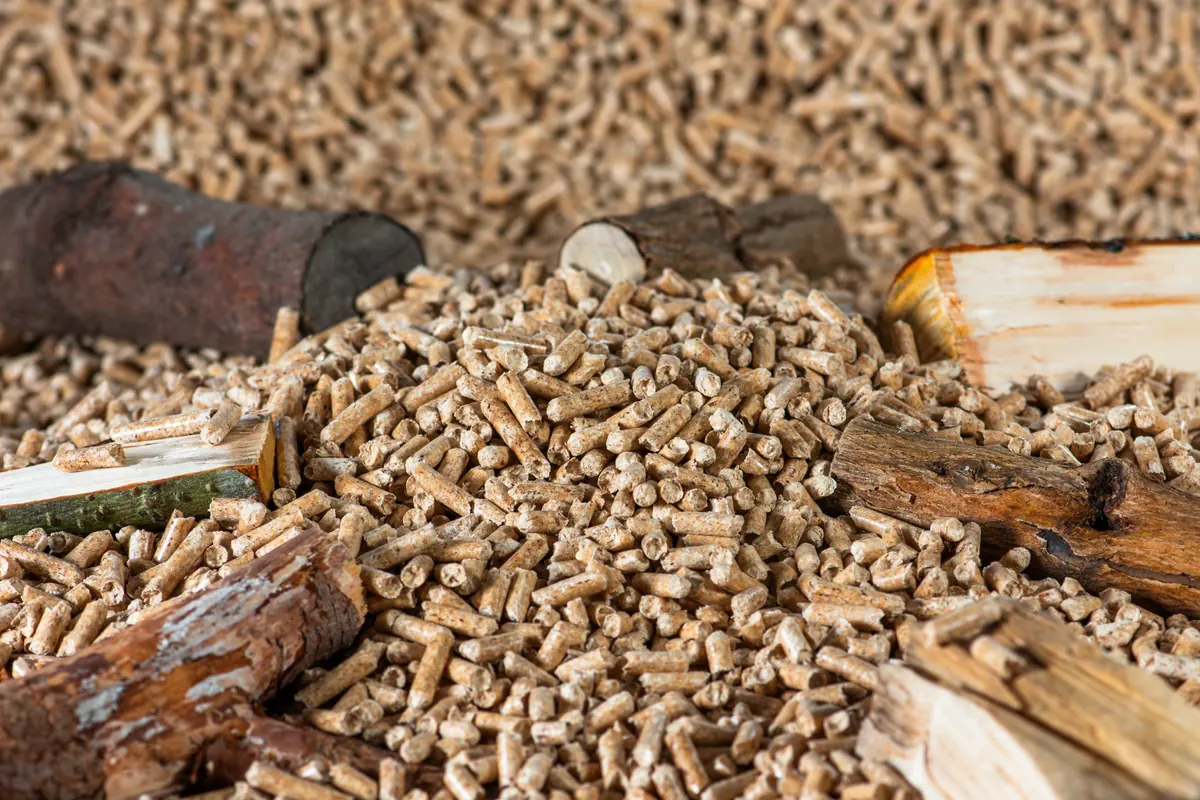 Haufen von Holzpellets zwischen Holzscheiten